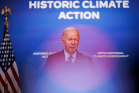 A man speaks in front of a backdrop that reads “historic climate action”