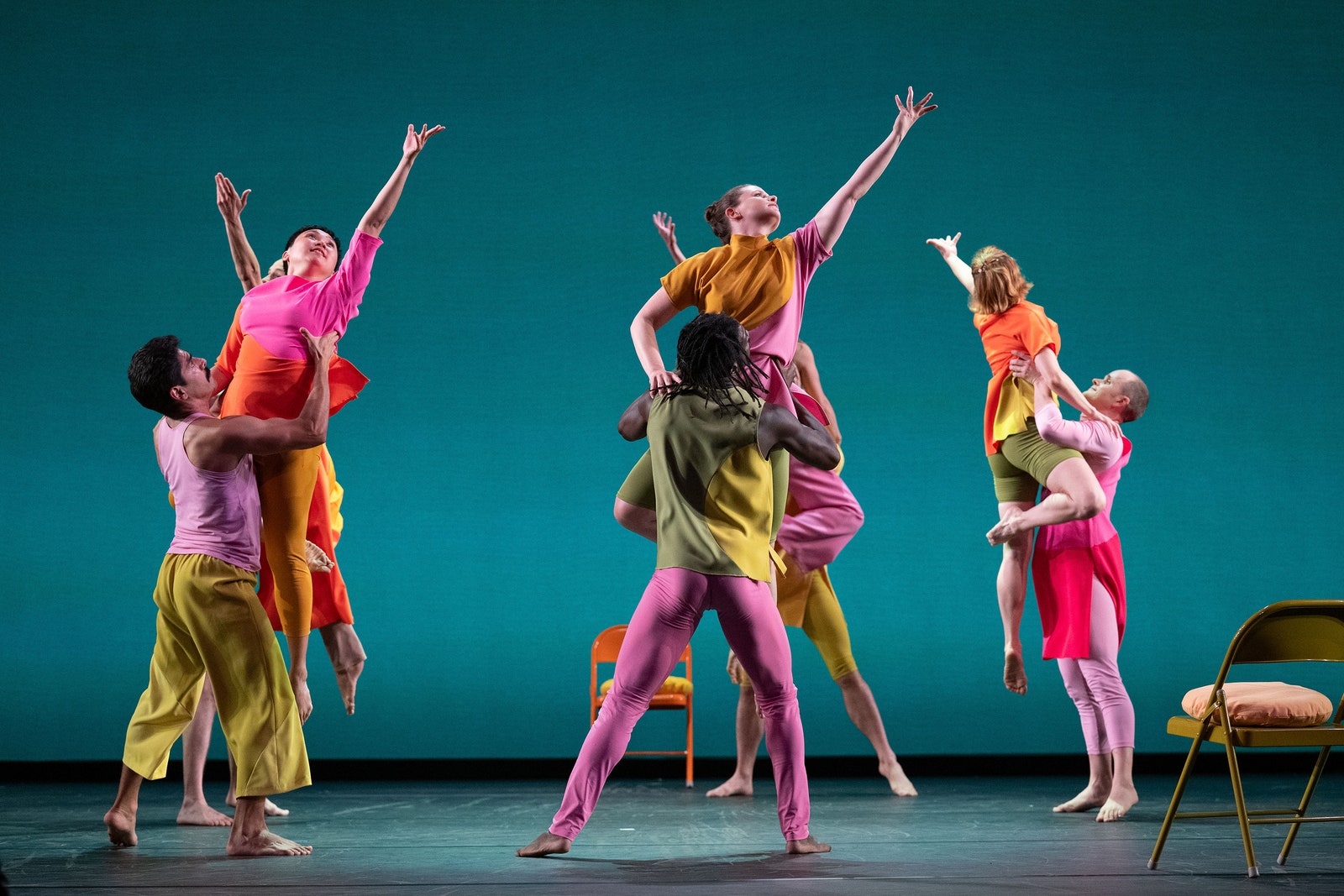 Dancers in multicolored costumes perform on a stage.