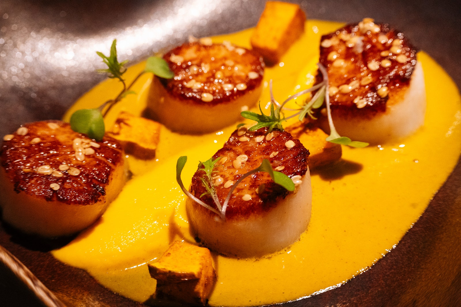 Scallops in a dish with a yelloworange sauce.