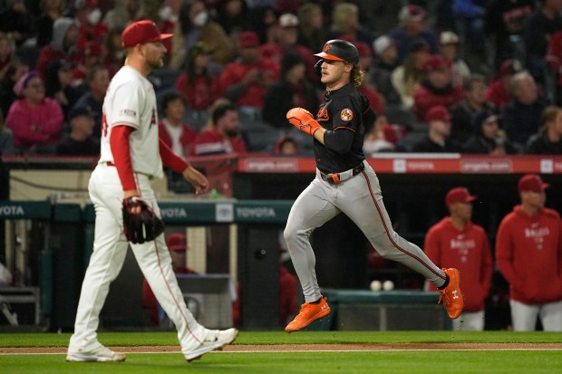 Baltimore Orioles' Gunnar Henderson, right, gets heads home to score...