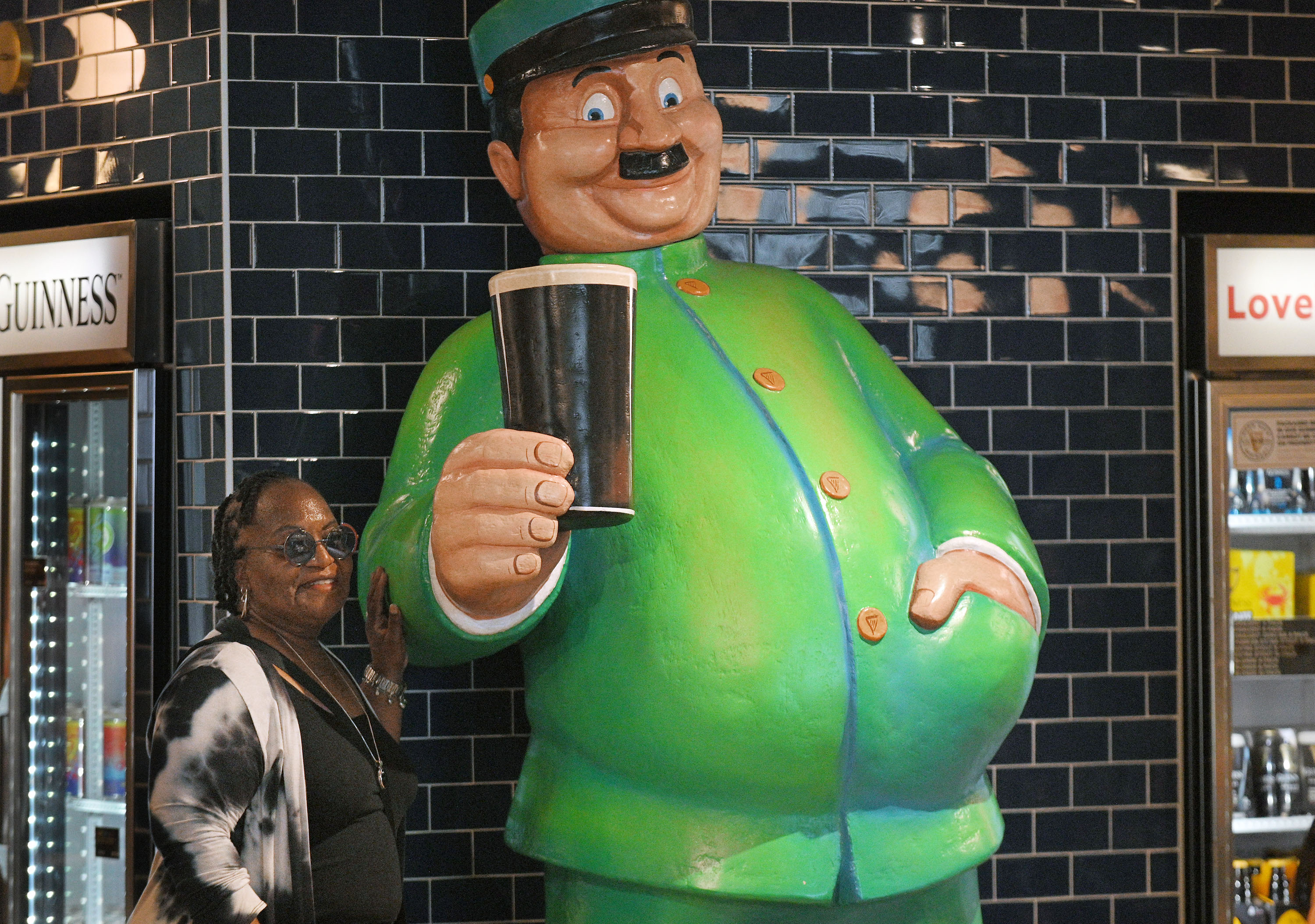 JoElla Brown Julius, of Lochearn, poses for picture with an oversized sculpture of British illustrator John Gilroy who produced much of Guinness brewery's advertising in the 1930s. Tours of the brewery is part of Baltimore County's Arts & Drafts Summer Music and Arts festival. The free two-day event presented by the nonprofit Baltimore County Arts Guild (BCAG) features curated artist vendors, live music, fun activities for all ages and specialty food & beers from host sponsor, Guinness Open Gate Brewery. (Kenneth K. Lam/Staff)