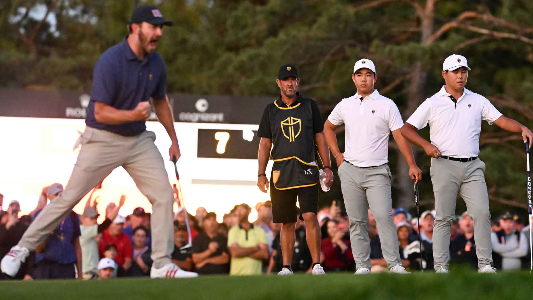 Tom Kim and Si Woo Kim of the International Team look on as Patrick Cantlay of the U.S. Team celebrates making a putt to win their match during Saturday Foursomes matches on day three of the 2024 Presidents Cup at The Royal Montreal Golf Club on September 28, 2024 in Montreal, Quebec.