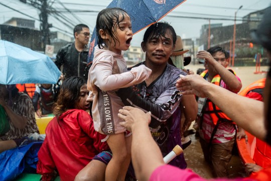 Rescuers assist a child getting off a boat along a flooded road following heavy rains brought by Typhoon Gaemi, in Marikina City, Metro Manila, Philippines, July 24, 2024. REUTERS/Lisa Marie David