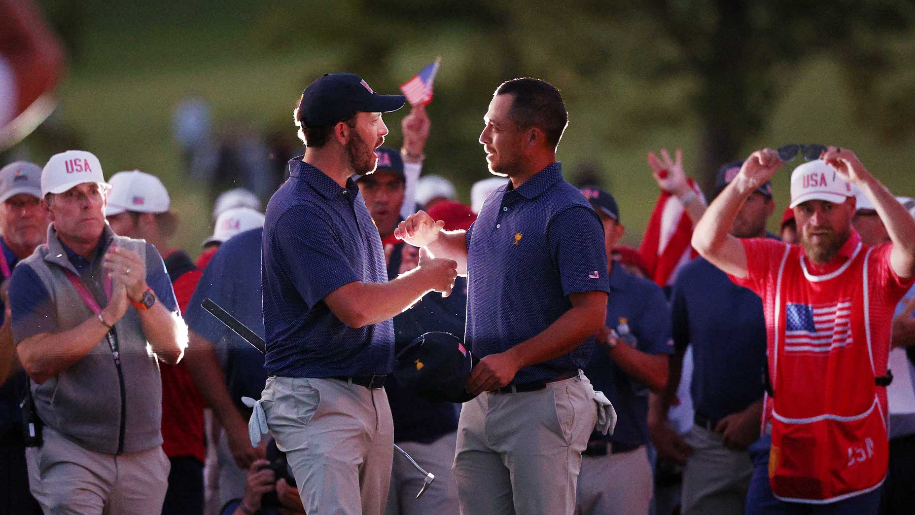 patrick cantlay and xander schauffele shake hands at the presidents cup in front of screaming fans