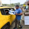 In this photo, Tony J. Daniel is holding a case of bottled water and is handing out bottles through the open back window of a yellow SUV in Old Fort, N.C., in the aftermath of Hurricane Helene on Sunday.