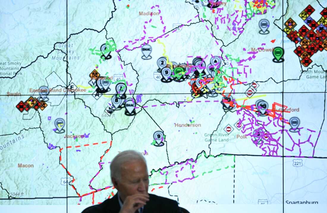 President Biden talks with state officials at an emergency operations center in Raleigh, N.C., with a map of the area hit by Hurricane Helene behind him.