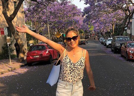 Linda in a leopard print top, standing in the middle of a road with her arm up in celebration