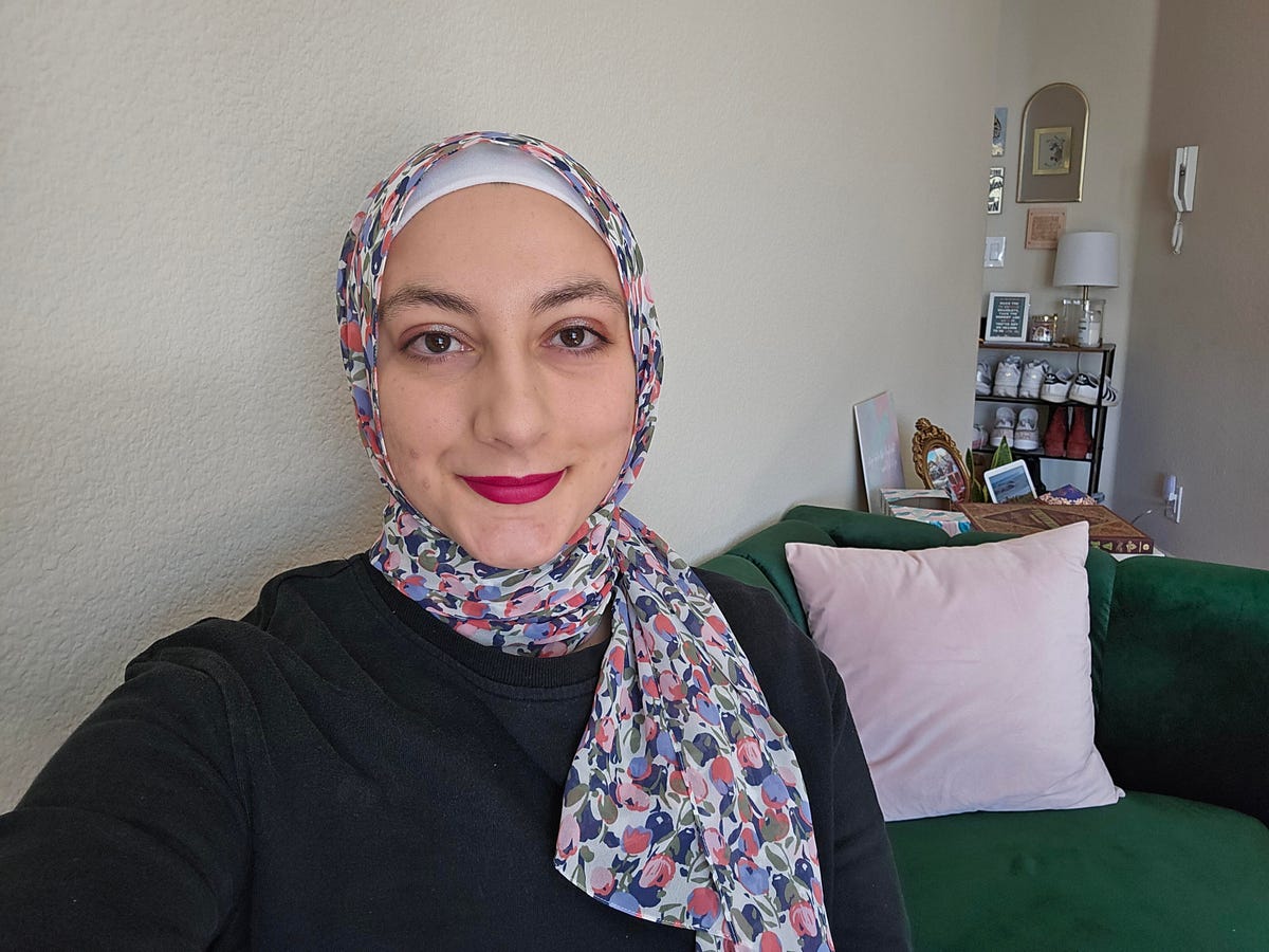 A woman in a colorful floral scarf sits on a velvet green couch