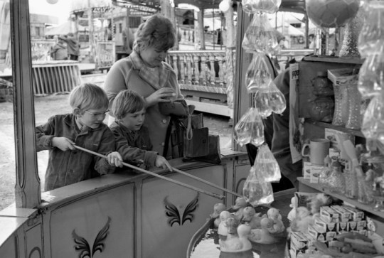 A black and white photo of children playing a duck hooking game at a fayre