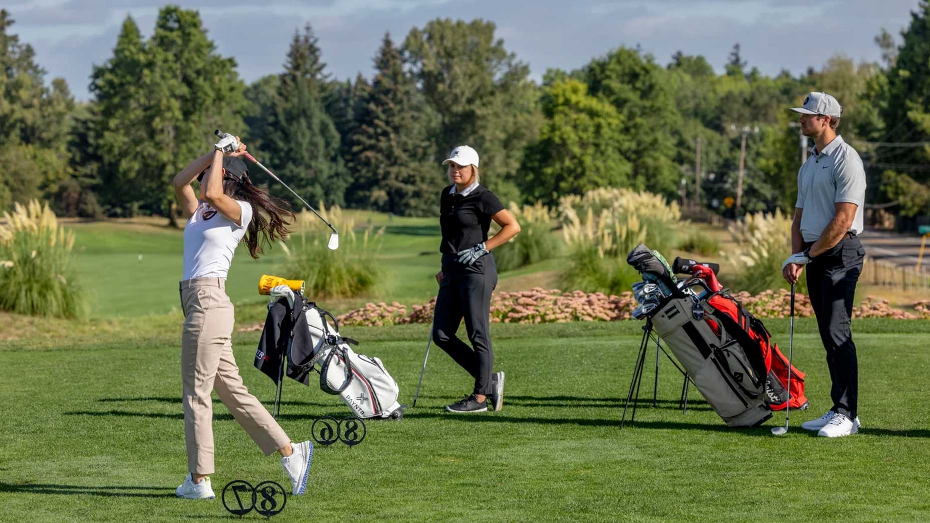 a group of golfers stand on a tee box