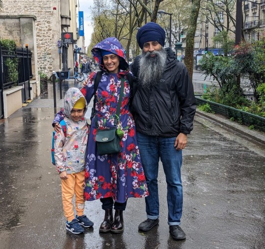 Karen standing in the rain with her husband and sob - wearing raincoats and smiling