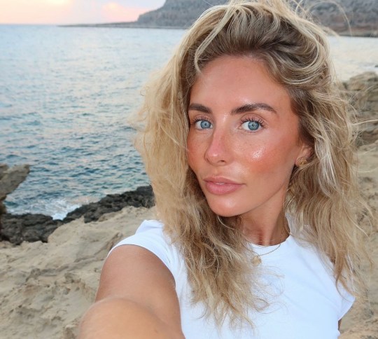 Bonnie Blue in a white top in Australia on the beach with windswept hair