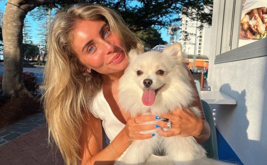 Bonnie Blue is smiling in a white top while holding a white fluffy dog