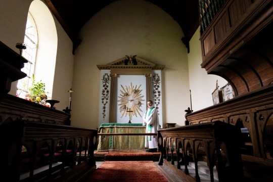 the vicar stands inside of the church 