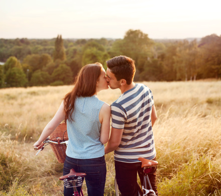 Couple kissing on bikes with view.