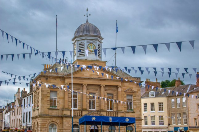 July 20, 2024 -Kelso, Scotland: View of the Town Hall in Kelso, Scotland surrounded by blue and white bunting on a cloudy evening. It is now home to the River Tweed Salmon Fishing Museum.