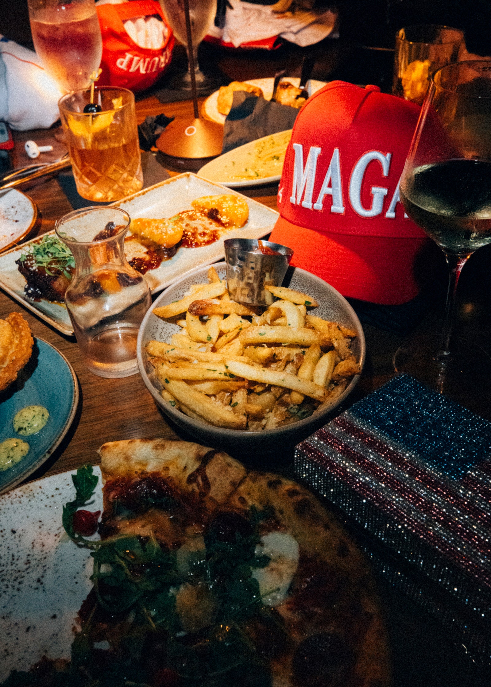 A red MAGA hat is shown on a table next to various foods.