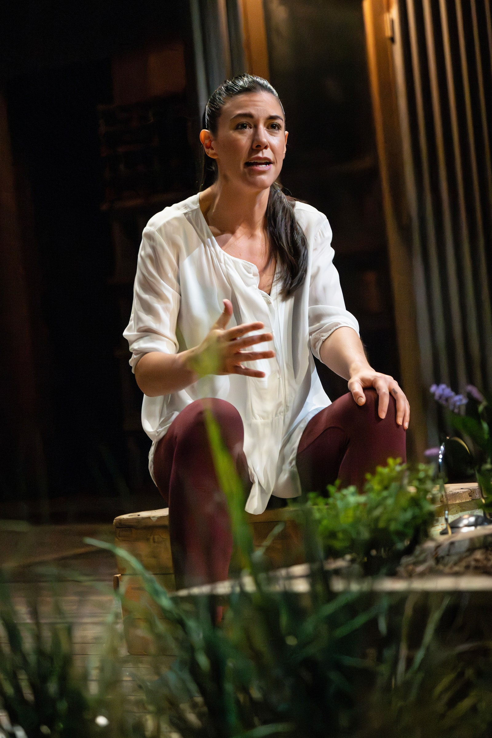 A woman in a white shirt on a stage gestures.